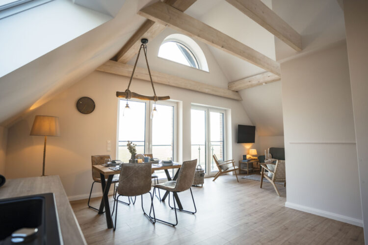 Heller Wohn- und Essbereich mit Dachbalken in der Ferienwohnung Kleiner Preuße auf dem Nordseehof Brömmer in Wremen