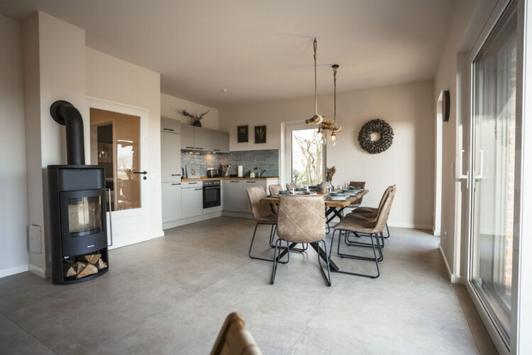 Moderner Wohnbereich mit Kamin und Küche in der Ferienwohnung Wattenbuttjer auf dem Nordseehof Brömmer in Wremen
