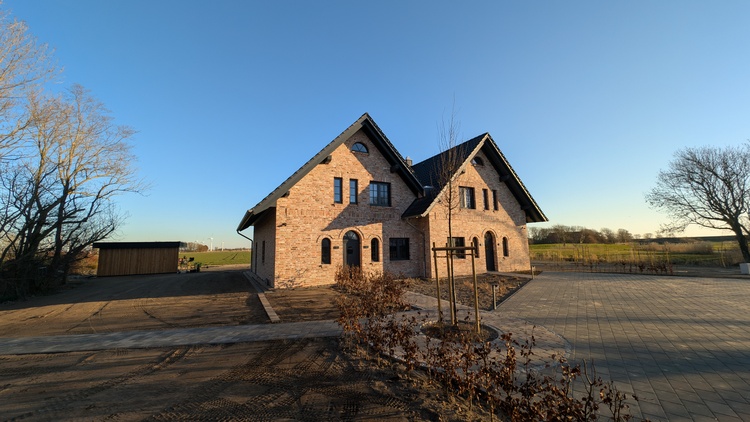Ferienhaus Deichhus mit roter Backsteinfassade auf dem Nordseehof Brömmer in Wremen bei Sonnenuntergang